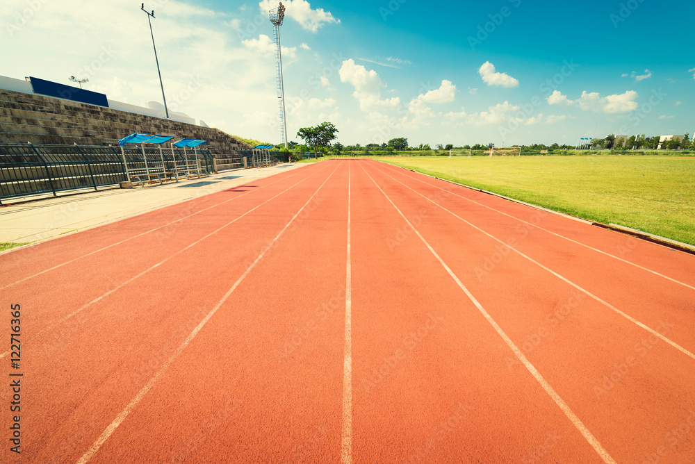 Fototapeta premium Red running track in stadium. Running track on blue sky.
