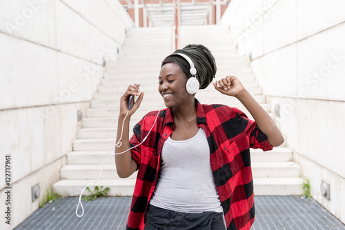 Fotografie Young black woman listening music with headphones and smart phone hand hold danc