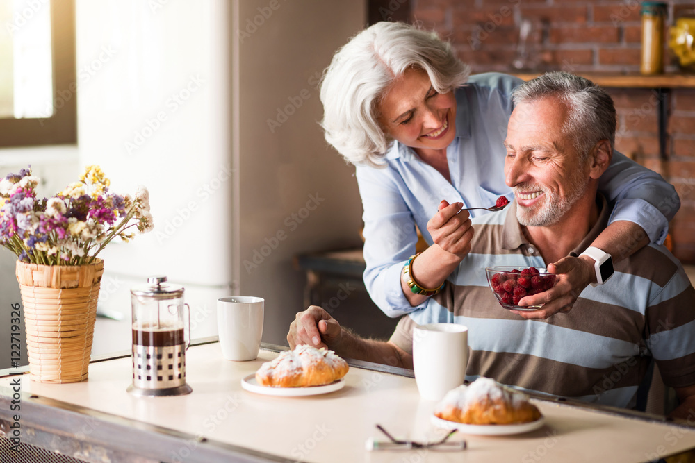 Elderly positive woman feeding her lovely husband. Elderly positive woman feeding her lovely husband.