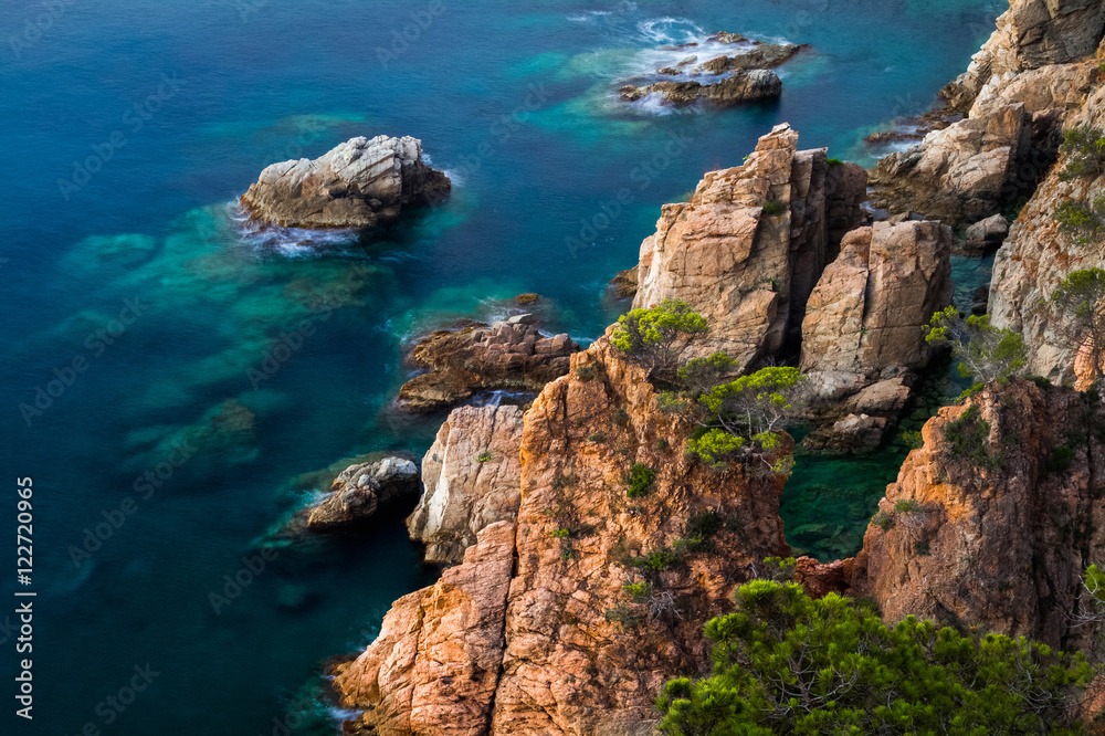Sea with rocks and transparent water at sunrise, Town of Tossa de Mar, Spain