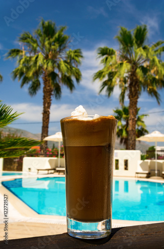 Ice Coffee at a poolside with palms in the background 