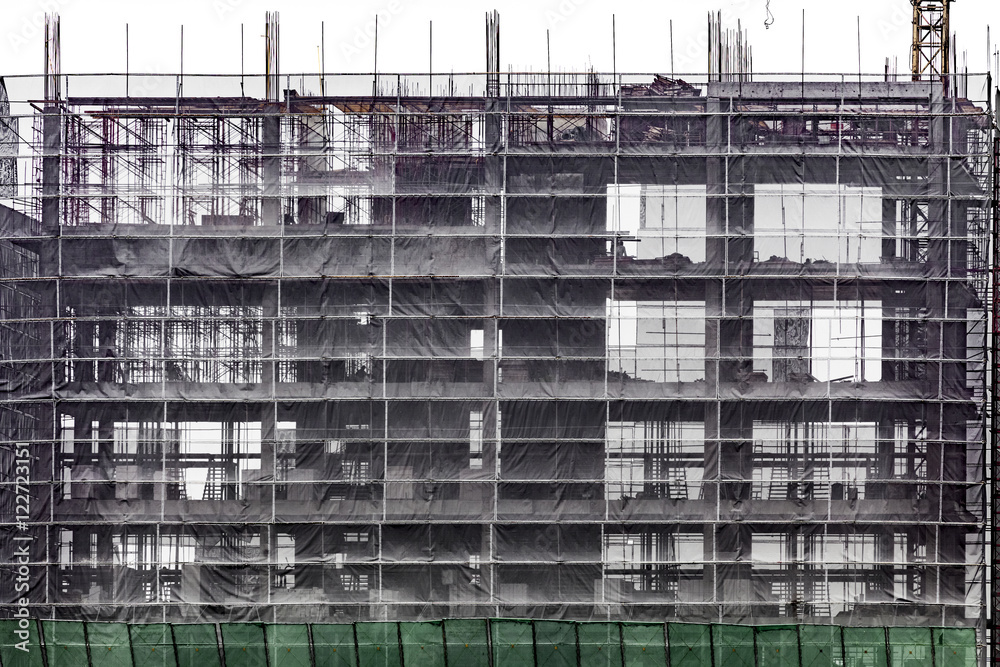 High-rise building under construction with protective bunting cover, Bangkok, Thailand