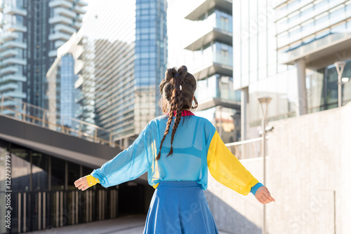 Back view of young woman with arms wide open outdoor in the city - freedom, emancipation, girl power concept