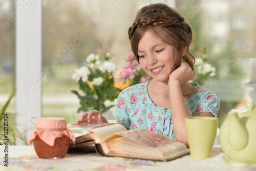 little girl reading book at home