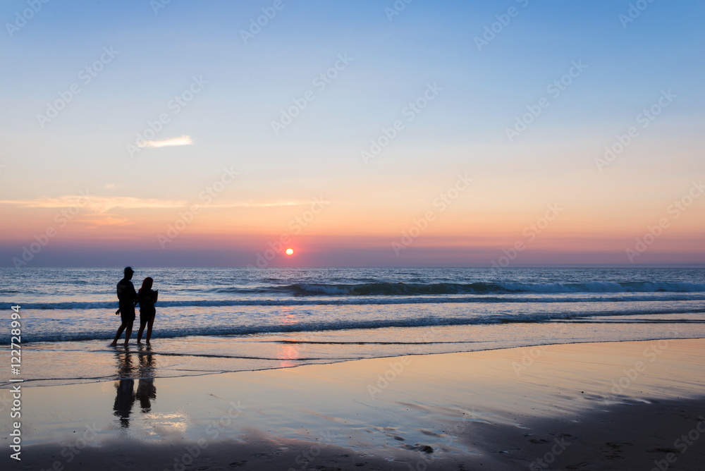 Silhouettes of a couple enjoying the sunset on the atlantic ocean, Lacanau France