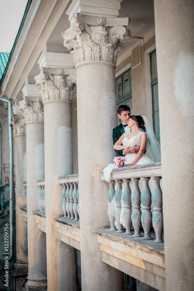 Young couple in love bride and groom posing near area with white columns on the background