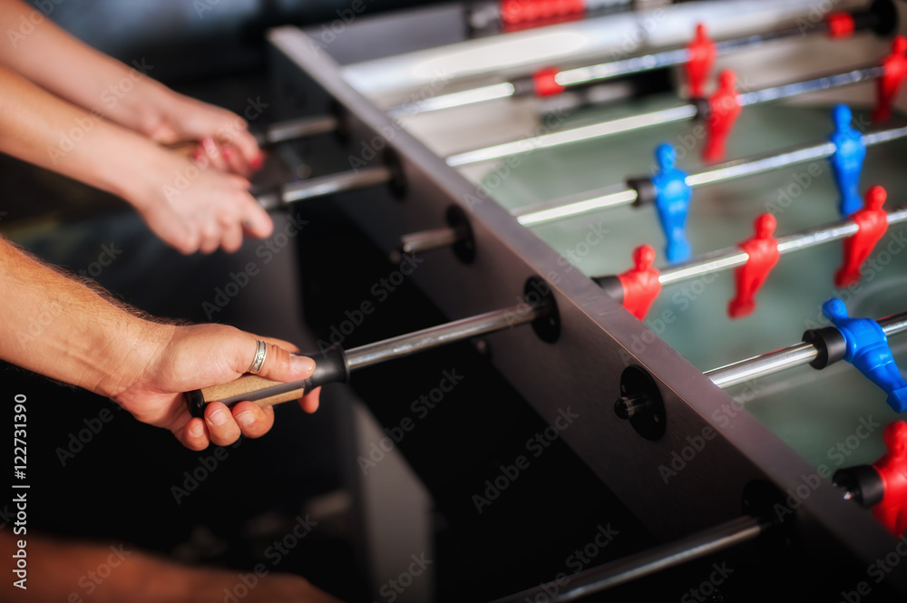 Friends having fun playing table foosball Friends having fun playing table foosball