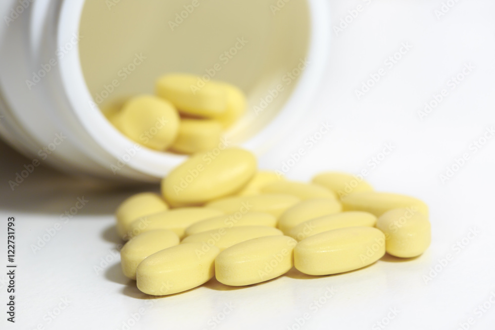 Closeup of small yellow pills that get out of an overturned plastic