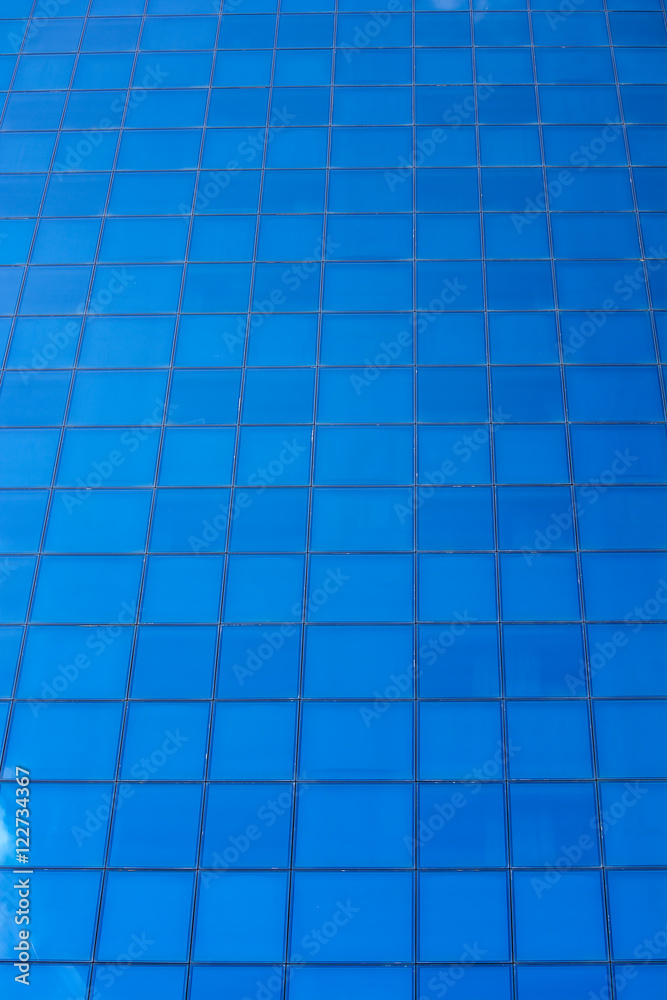 The glass facade of a modern building. High building. Reflection of the sky in the windows. The glass facade of a modern building. High building. Reflection of the sky in the windows.