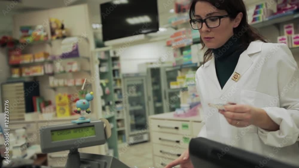 A pharmacist woman gives the rest to a customer. A pharmacist woman gives the rest to a customer.