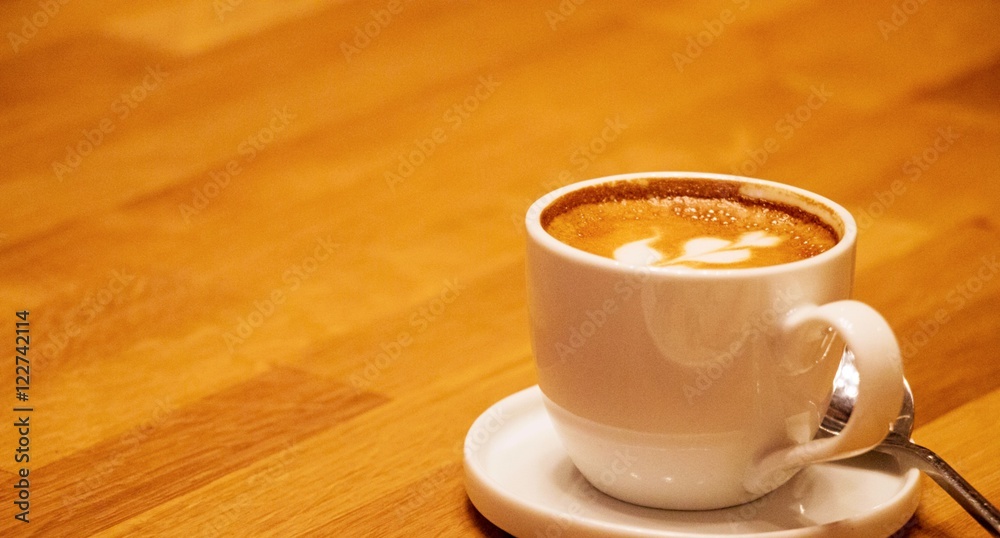 Coffee in white cup with coffee arts on the top on the wooden tray Coffee in white cup with coffee arts on the top on the wooden tray