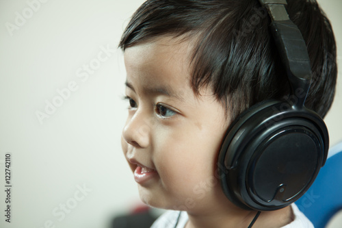 Happy Asian boy ware headphone and playing the cell phone on gra