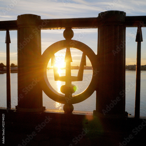 Trident symbol at bridge banister against rising sun 