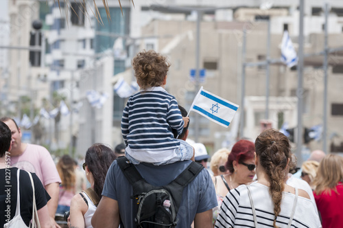 Father and a child walking with the crowd in the Tel Aviv promenade during the Independence Day of Israel. Tel Aviv, Israel, May 2014. Stock photo image. photo