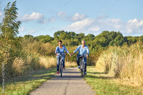 Radfahren in der Natur, lachendes Seniorenpaar mit Fahrrädern