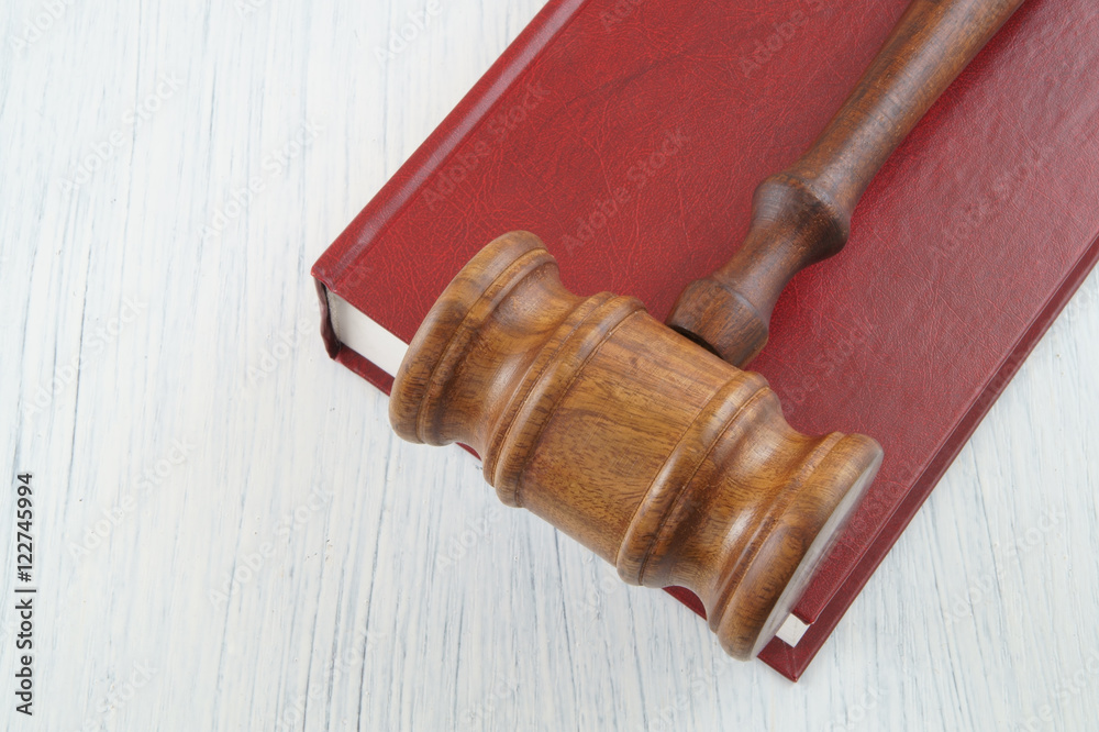 Wooden judge's gavel on red legal book