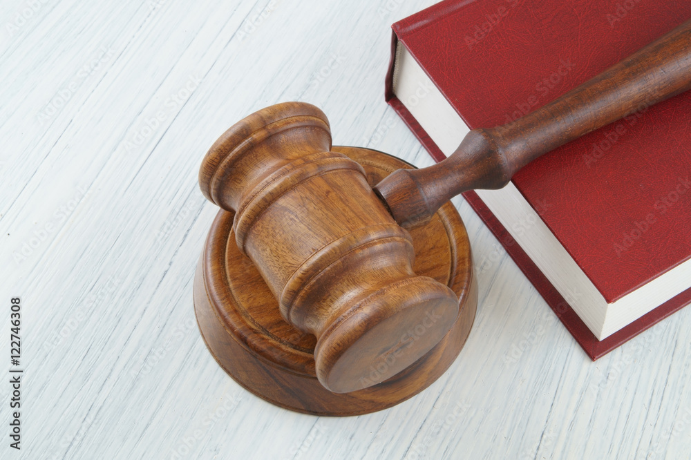 Wooden judge's gavel on red legal book