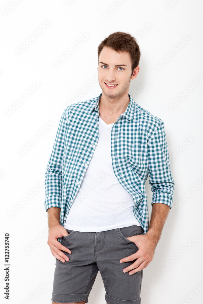 Fototapeta premium Young man standing against white background. Happy young man. Portrait of handsome Man in casual shirt and smiling while standing against at white wall