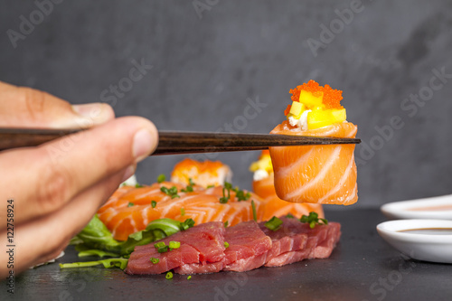 Hand with chopsticks holding salmon sushi nigiri
