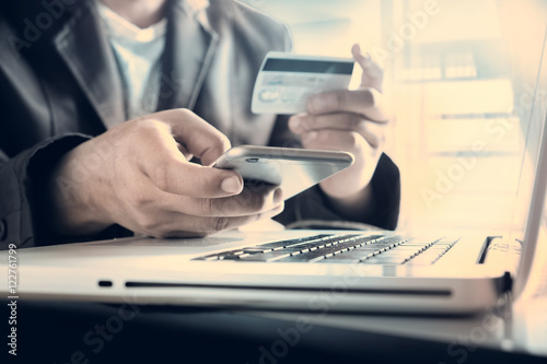 Man's hands holding a credit card and using smart phone for onli