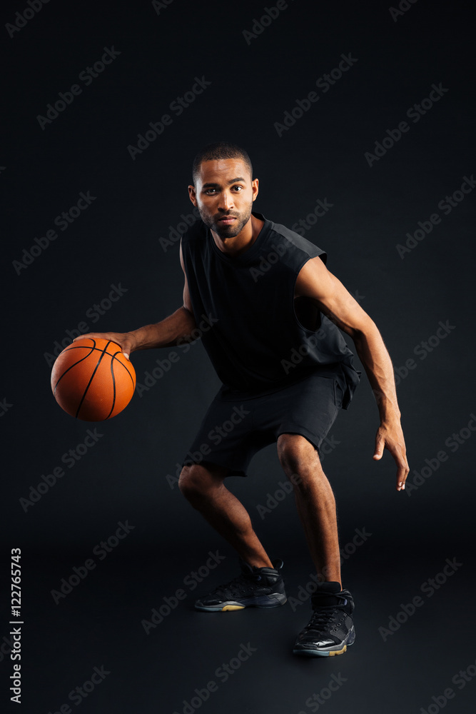 Full length portrait of an concentrated african man playing basketball