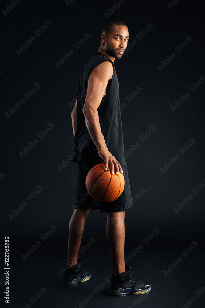 Side view of a concentrated basketball player looking over shoulder Side view of a concentrated basketball player looking over shoulder