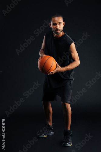 Full length portrait of a serious african sportsman playing basketball © Drobot Dean