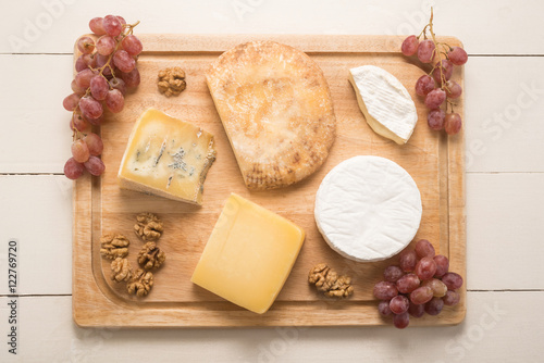 Cheese with grapes and walnuts on a wooden table 
