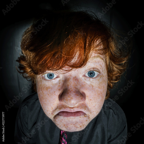 Emotive portrait of red-haired freckled boy  childhood concept