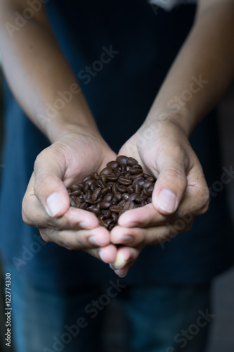 Man holding coffee beans in cupped hands, close-up 