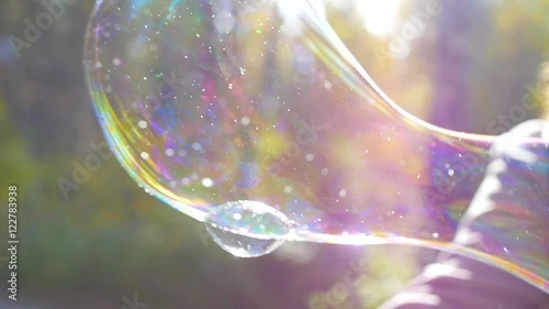 girl blowing large soap bubbles closeup in sunlight