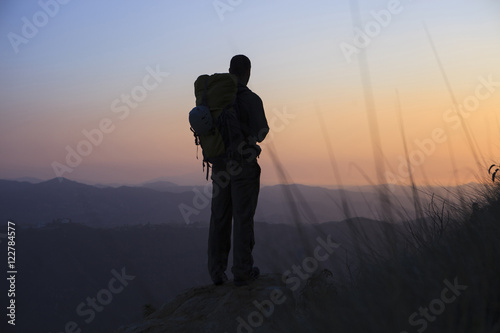 Silhouette man standing on rock and looking at view during sunset photo