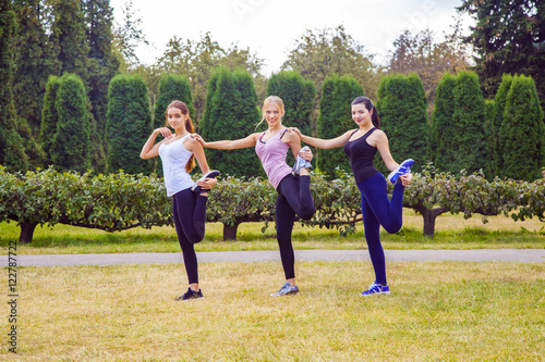 The group of three beautiful young women doing sport in sunny day in the park. happiness and health care sport outdoors.