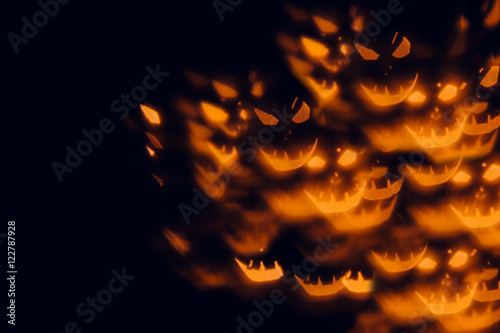 Halloween festive blurred background. Orange pumpkin faces on a black background.