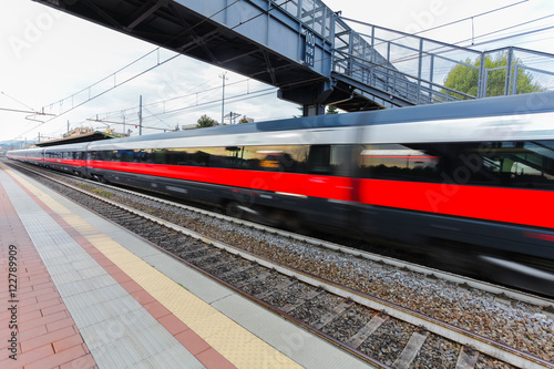High speed passenger trains on railroad platform in motion. Blur effect of commuter train. Railway station in Florence, Italy. Industrial landscape photo