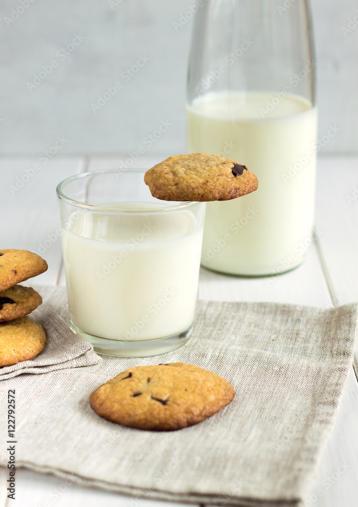 Homemade cookies with chocolate pieces and milk on a white table. Homemade cookies with chocolate pieces and milk on a white table.