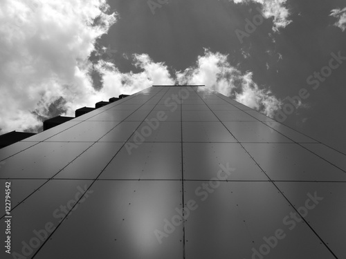 Looking up on high administration building with sky and clouds in black and white