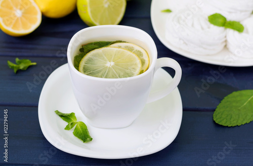 Healthy ginger tea with lemon, lime and mint on table close-up. Healthy drink. Autumn, winter beverage concept.