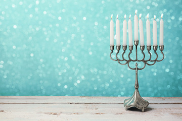 Menorah with candles for Hanukkah celebration over bokeh background