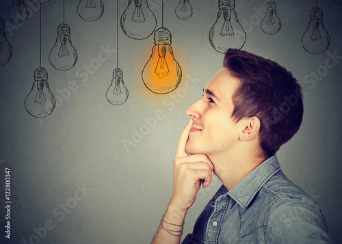 Thinking man looking up with light idea bulb above head photo