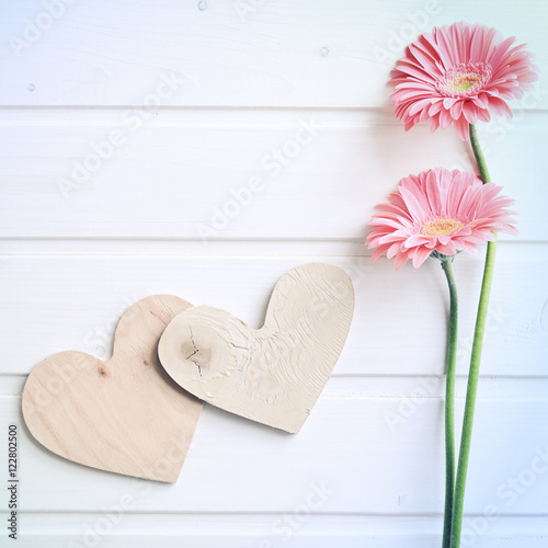 Two pink gerber daisy flowers on  wooden backgraund. Gerbera and decorative heart. Flat lay, top view photo