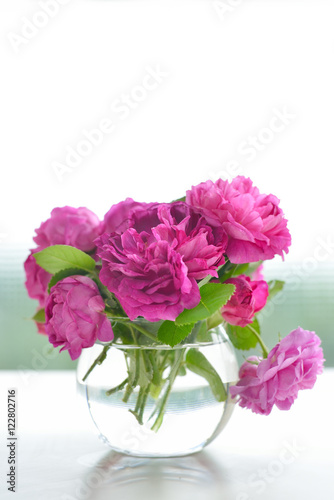 Beautiful bouquet of pink rose flowers in glass vase with green bokeh background