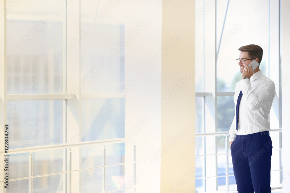 Handsome young lawyer talking on phone at office building Handsome young lawyer talking on phone at office building