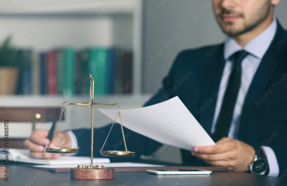 Naklejka premium Scales of justice and businessman sitting at table