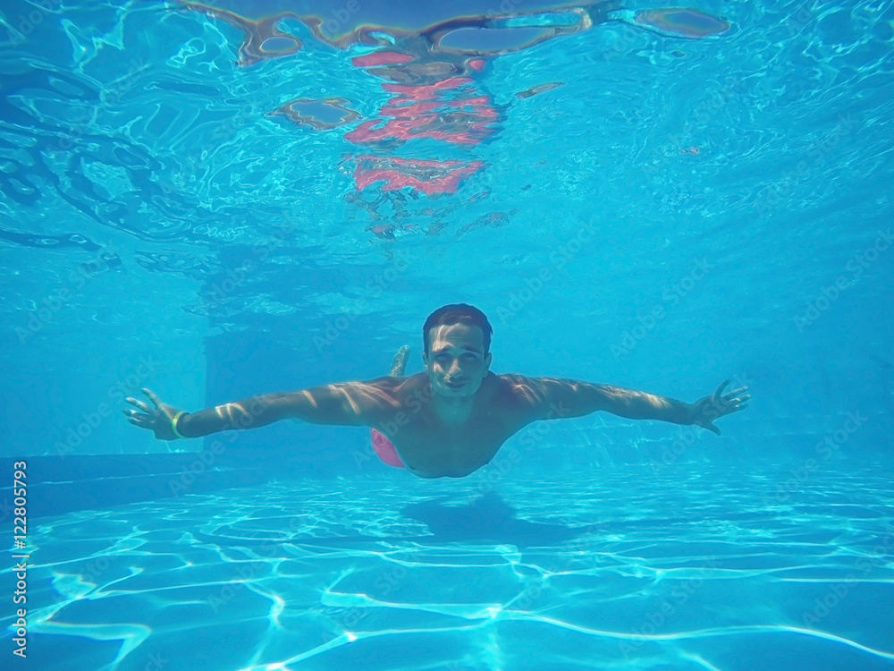 Sporty young man swimming underwater in pool