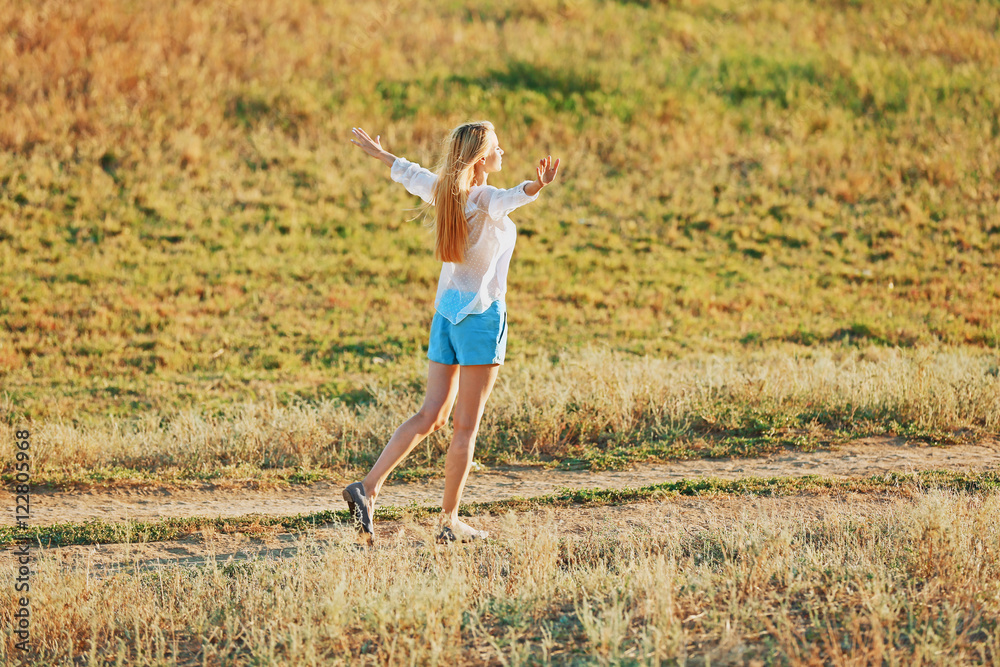 Young woman walking on field background Young woman walking on field background