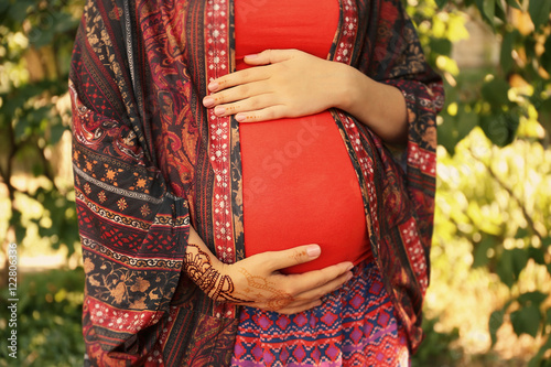 Young pregnant woman with henna tattoo on hand in park