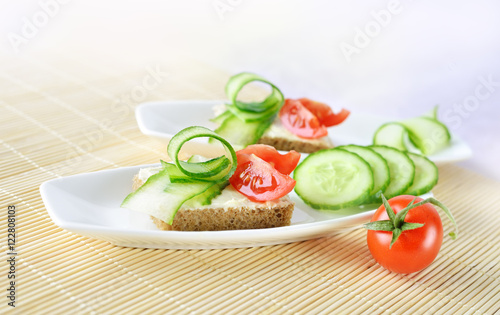 Canapes with butter, cucumber and tomatoes