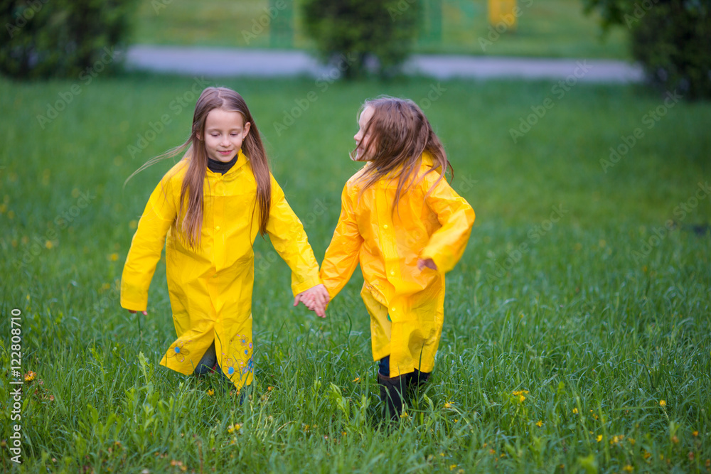 Adorable little girls under the rain on warm autumn day Adorable little girls under the rain on warm autumn day