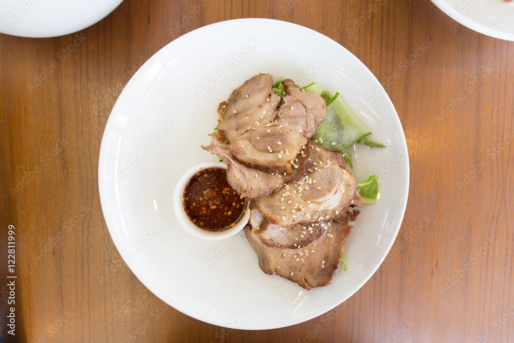 Fried sliced pork with garlic in white dish on wood table Fried sliced pork with garlic in white dish on wood table